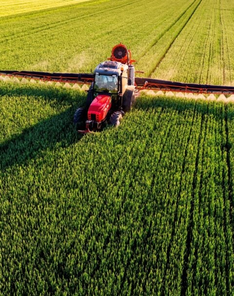 Drone,Shot,Of,A,Farmer,In,Red,Tractor,Spraying,Pesticides